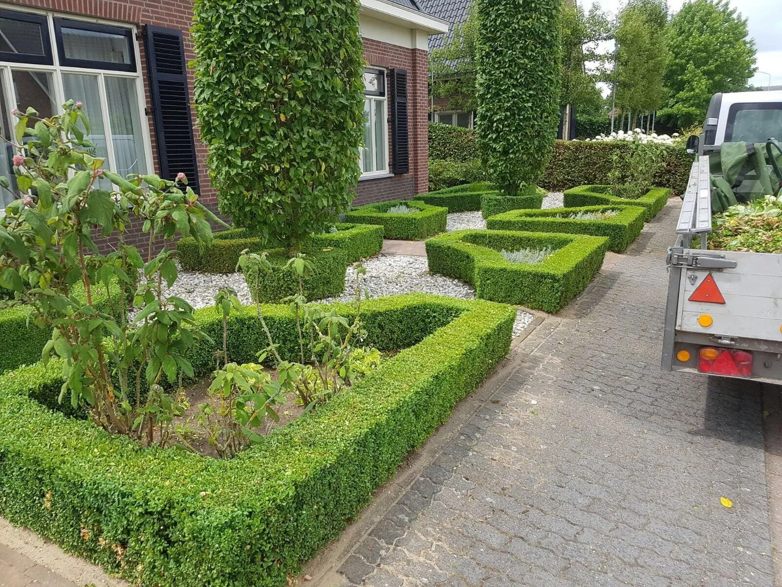 Gesnoeide buxushagen en bomen langs een tuinpad