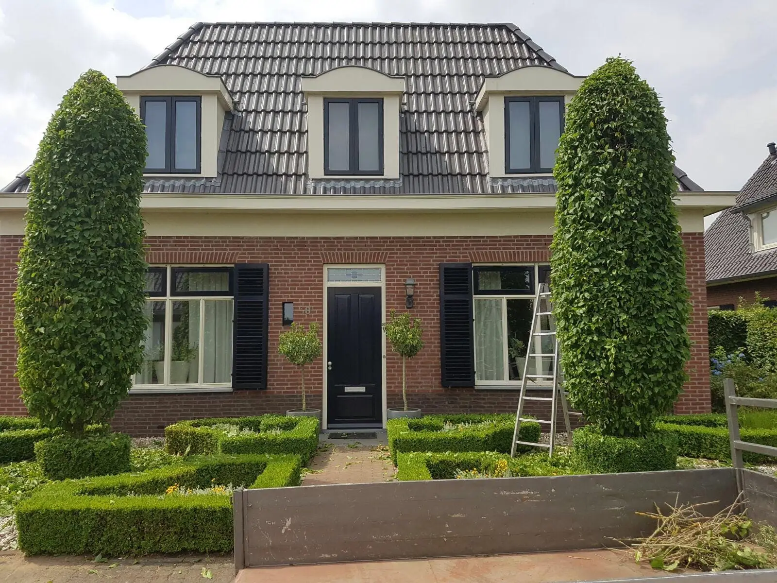 Strak gesnoeide buxushagen en zuilbomen in een voortuin