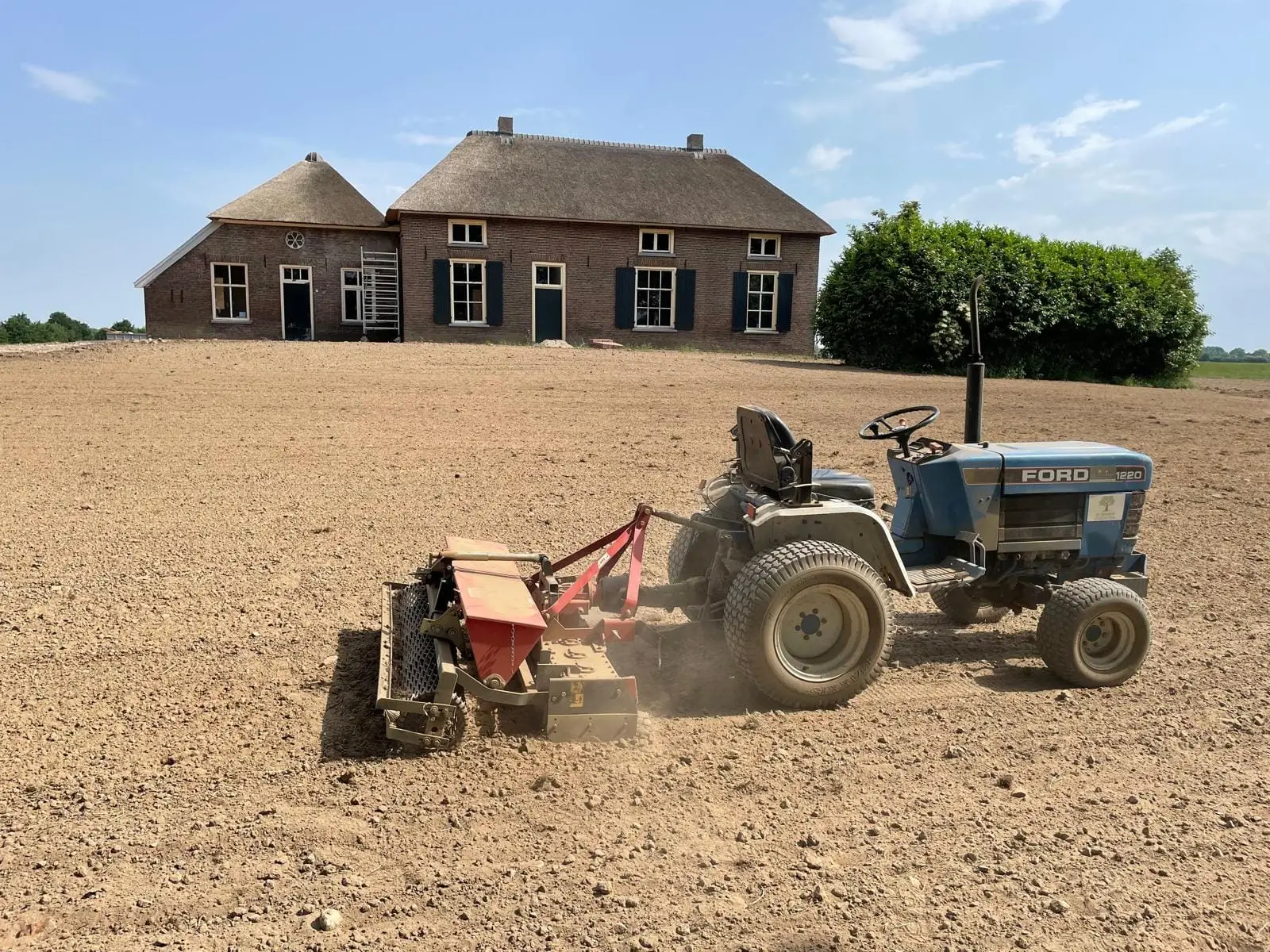 Grond egaliseren met een trekker bij een woonboerderij