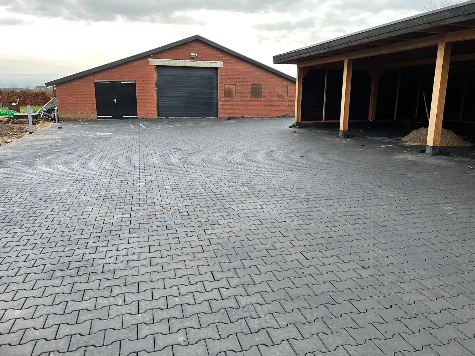 H-verband bestrating op een erf met schuur en overkapping