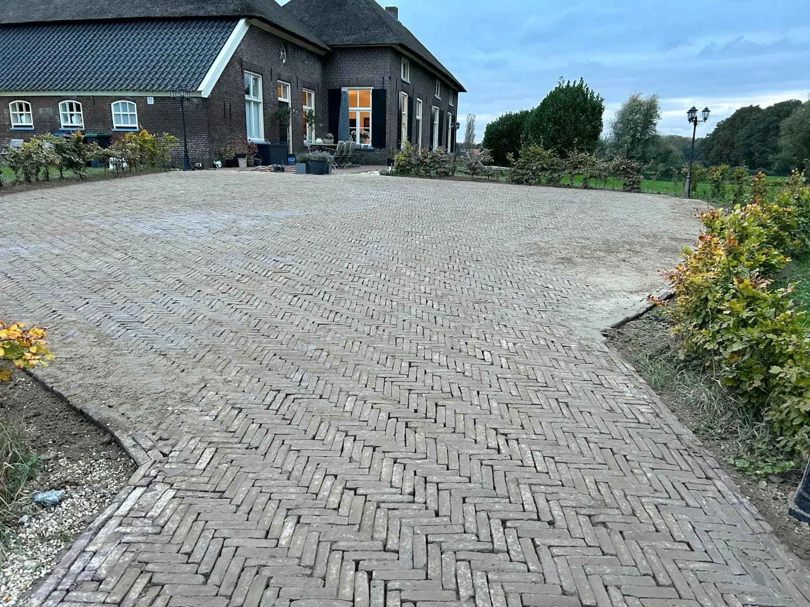 Nieuwe klinkerbestrating in visgraatverband bij een woonboerderij