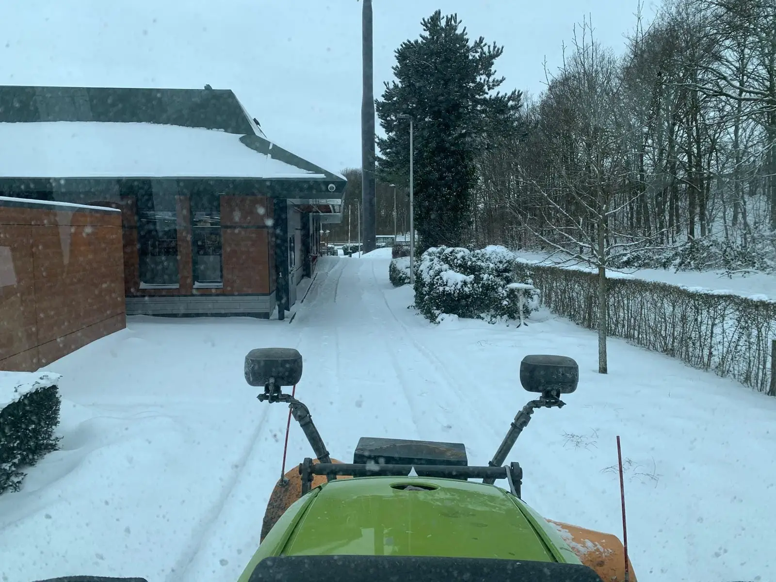 Sneeuw schuiven met een trekker op een bedrijfsterrein