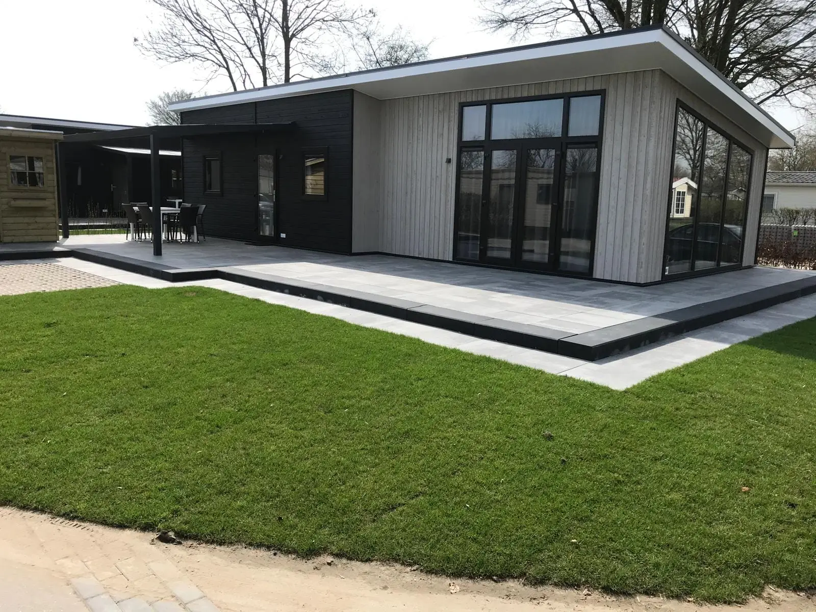 Strak terras en nieuwe graszoden bij een chalet