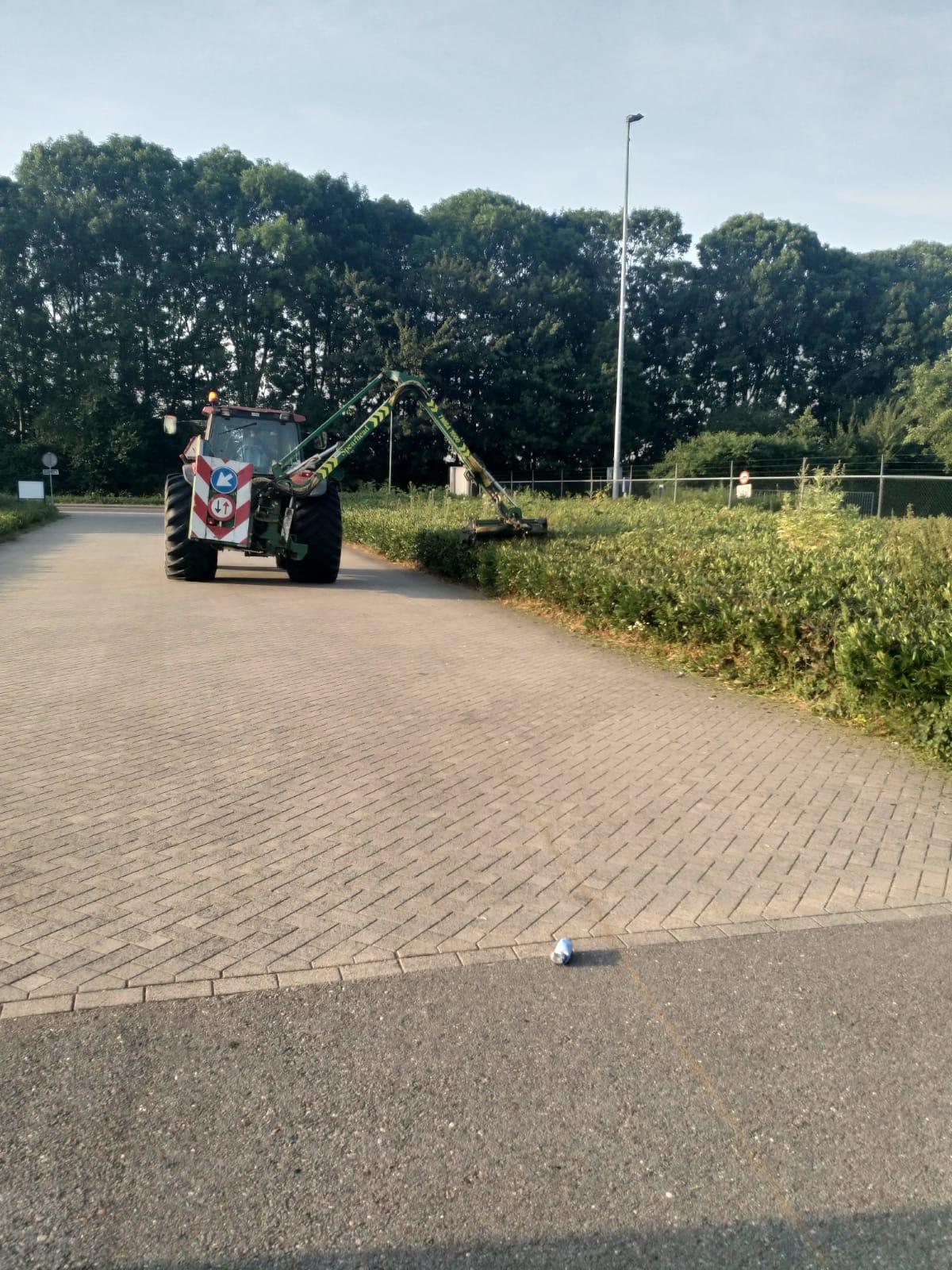 Machinaal snoeien van struiken met een tractor op een bedrijventerrein, uitgevoerd door De Tuynderie.