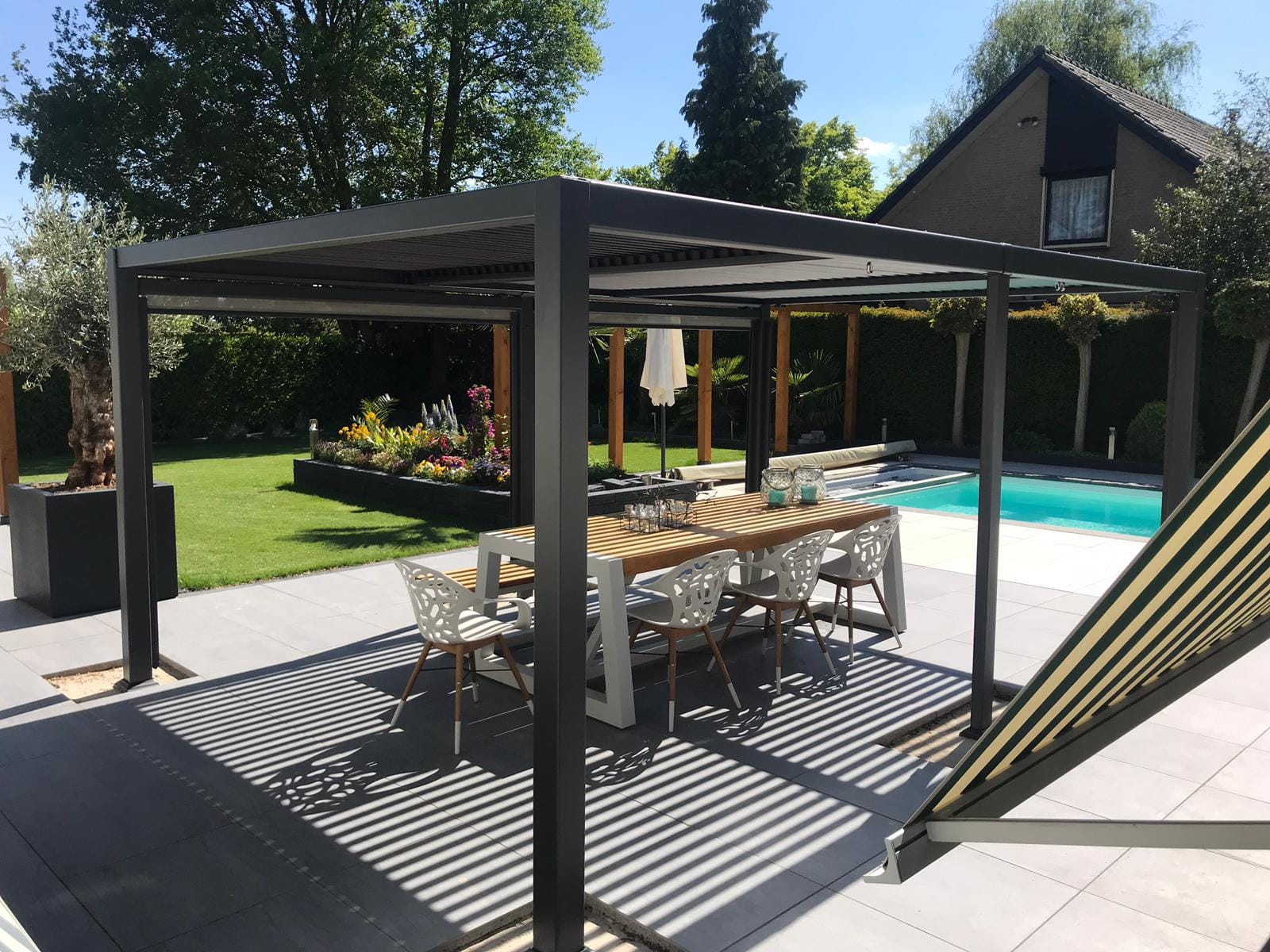 Stijlvolle tuin met moderne overkapping, ontworpen en aangelegd door De Tuynderie.